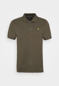 Polo shirt vert olive foncé en coton. Il dispose d'une patte de boutonnage à trois boutons, de manches courtes et d'un petit logo brodé jaune sur la poitrine.