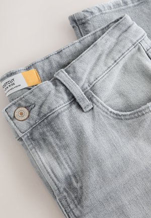 Lysegrå denimjeans med lav talje, der har knaplukning, standardlommer og en mærkat synlig på linningen.