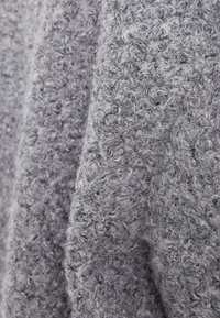 Šedá texturovaná tkanina s smyčkovým vzorem a měkkým, chlupatým povrchem, ideální pro teplo a pohodlí.