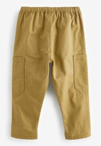Pantalons en coton beige avec une taille élastique, deux poches cargo latérales et une coupe droite. Texture lisse avec des coutures surpiquées.