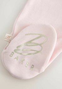 Lyserød stofhandske med et glat, skinnende gyldent "B" logo og "BAKER" tekst. Har en blød overflade og afrundet form, med et lille mærke synligt.