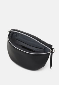 Černá kožená taška se zakřiveným tvarem, stříbrným zipem a vnitřní kapsou. Podšita šedou látkou, která má hladkou texturu.