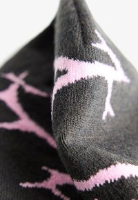 Calzini lavorati a maglia con una base grigia scura e un motivo testurizzato in rosa. Il design include forme astratte e dettagli di cucitura fine.