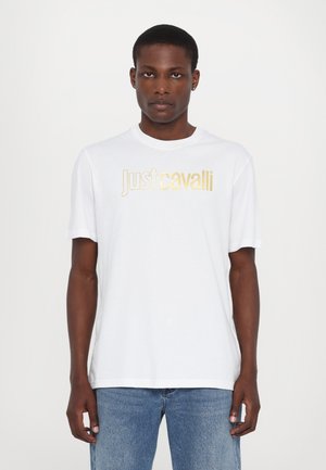 Hvit bomull T-skjorte med korte ermer, med "Just Cavalli"-logo i gulltrykk. Enkel rund hals-design, glatt tekstur.