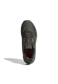 Chaussures de sport en mesh vert foncé avec des accents gris. Présentent un dessus texturé, des lacets noirs et une semelle intérieure orange marquée "TERREX."