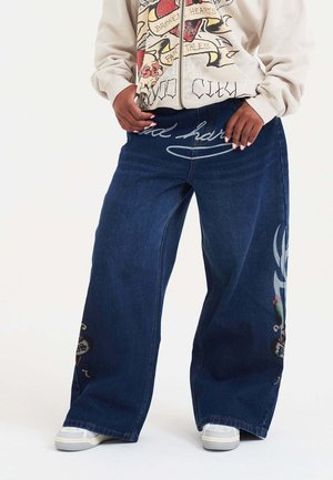 Szerokie ciemnoniebieskie dżinsy z dekoracyjnym nadrukiem z przodu oraz szczegółowymi akcentami na dolnej części nogawek.
