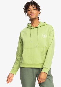 Hoodie verde chiaro con tasca frontale, cappuccio con cordoncino e piccolo logo del sole bianco sul lato sinistro del petto. Il tessuto sembra morbido e leggermente testurizzato.