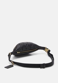 Sac banane en cuir noir matelassé avec fermeture éclair et boucle dorées, sangle noire réglable et petite étiquette attachée sur fond blanc.