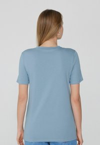 Bavlněné tričko v světle modré barvě, s krátkými rukávy a klasickým kulatým výstřihem. Hladká textura, bez viditelných vzorů nebo akcentů.