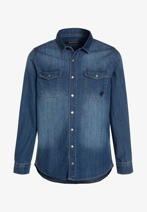 Camisa vaquera azul de manga larga con botones de presión, dos bolsillos en el pecho con solapas y cuello en punta. No hay modelo visible, la camisa está abotonada.