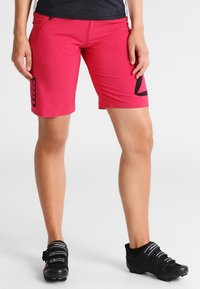 Bright pink cycling shorts made of stretchy material, featuring a side pocket and a black graphic design. Trimmed for comfort and mobility.