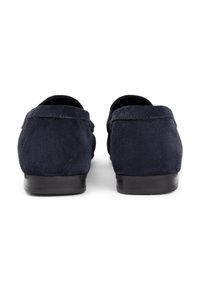 Μοκασίνια σε ναυτικό μπλε σουέντ με χαμηλό μαύρο τακούνι, με λεία υφή και ελάχιστες ραφές στο πίσω μέρος.