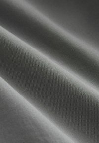Tissu lisse gris clair avec de fines côtes diagonales et des plis doux créant des ombres et des reflets délicats.