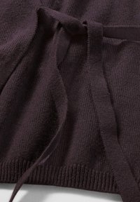 Dunkelviolette Strickumhüllung mit strukturierter Oberfläche, ausgestattet mit einem breiten Band und geripptem Saum. Das Material ist weich und könnte Wolle oder Baumwolle ähneln.