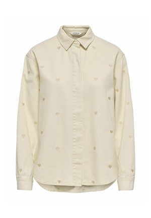 Chemise à manches longues couleur crème avec de petits motifs de cœurs brodés répartis uniformément sur le tissu.