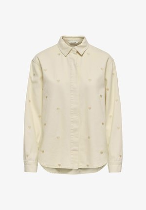 Chemise à manches longues couleur crème avec de petits motifs de cœurs brodés répartis uniformément sur le tissu.