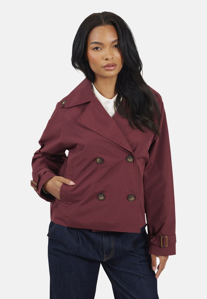 Veste double boutonnage bordeaux avec de grands boutons marron, un large col et des sangles de poignet ajustables. Tissu léger, coupe décontractée, poches latérales.