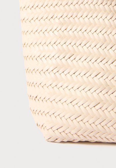 Vävd shoppingväska i ljusbeige, tillverkad av mjukt läder. Har ett fiskbensmönster med en slät yta och sömlösa kanter.