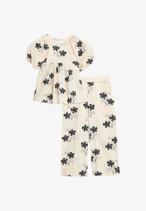 Zweiteiliges Kinderoutfit mit einem cremefarbenen Oberteil mit Puffärmeln und schwarzem Blumenmuster, kombiniert mit passenden Hose im gleichen floralem Design.