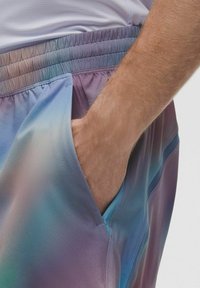 Pantalones cortos deportivos multicolores con cinturilla elástica, que presentan una textura suave y degradada en tonos de azul, púrpura y rosa, con bolsillos laterales.