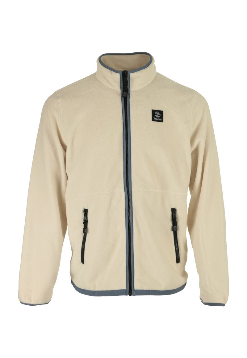 Giacca in pile beige con colletto alto, chiusura frontale a zip e due tasche laterali. Presenta zip nere e un bordo blu lungo il fondo.