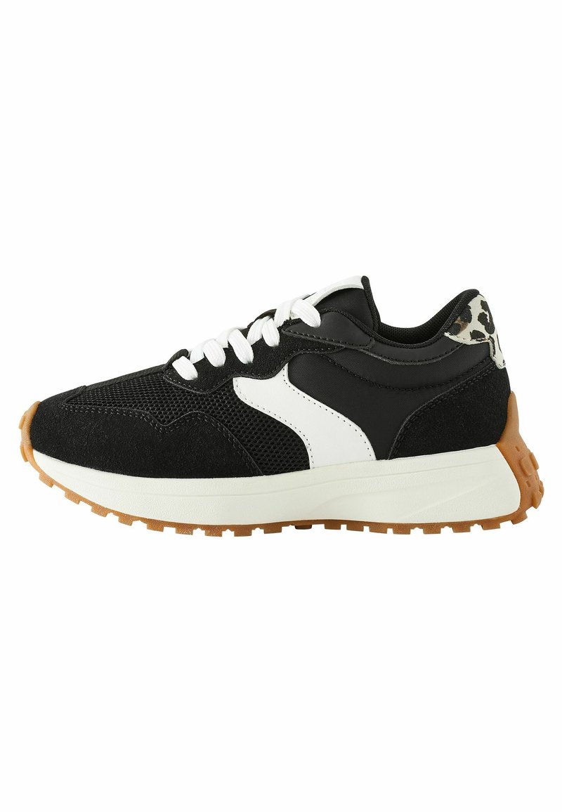 Chaussure de sport noire avec des accents blancs et imprimé léopard, en matériaux mesh et daim, lacets blancs et semelle en caoutchouc de gum.