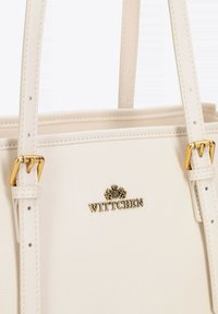 Borsa beige in pelle con manici doppi, accessori in metallo dorato e un logo sul davanti. Texture liscia con dettagli di cucitura.