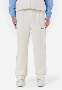 Cremefarvede sweatpants med lyseblå sidestriber, lavet af blødt stof, med et broderet logo på venstre lår.