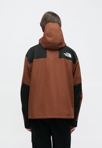 Καφέ και μαύρο μπουφάν με κουκούλα, με λεία υφή και σχεδιασμό με αντιθετικές πινελιές. Λογότυπο στο πάνω μέρος της πλάτης, άνετη εφαρμογή.