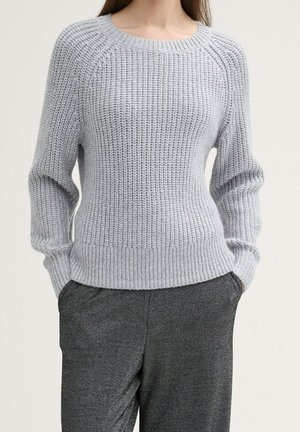 Hellgrauer gerippter Strickpullover mit Rundhalsausschnitt und langen Ärmeln, der eine strukturierte Oberfläche und einen schmal zulaufenden Saum aufweist. Trägt man mit dunklen Hosen.