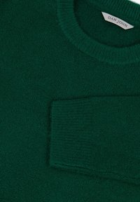 Suéter verde de punto con un acabado texturizado, cuello redondo y un bolsillo de parche en la parte frontal izquierda. La etiqueta dice "DAN JOHN".