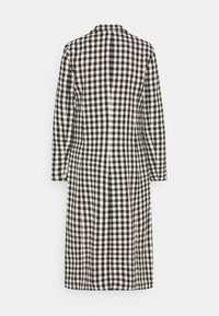 Zwart-witte geruite jas met een lang ontwerp, voorzien van een naad aan de achterkant. Gemaakt van een gestructureerde stof, het heeft een kraag en lange mouwen.