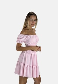 Roze tweedelig outfit bestaande uit een off-shoulder cropped top met pofmouwen en een gelaagde, gerimpelde minirok met een elastische tailleband.