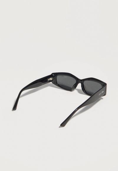 Μαύρα γυαλιά ηλίου με ορθογώνιο πλαίσιο και σκούρους φακούς, εμφανιζόμενα από πάνω σε λευκό φόντο.
