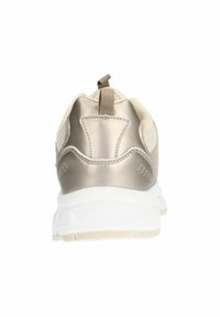 Chaussure de sport beige avec une tige en mesh texturé, des accents métalliques au niveau du talon et une semelle en caoutchouc blanc. Dispose d'une languette à l'arrière pour un enfilage facile.