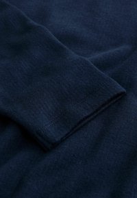 Navy blue sweatshirt fabric with a soft texture, featuring a rolled cuff detail, subtle stitching, and a smooth surface.