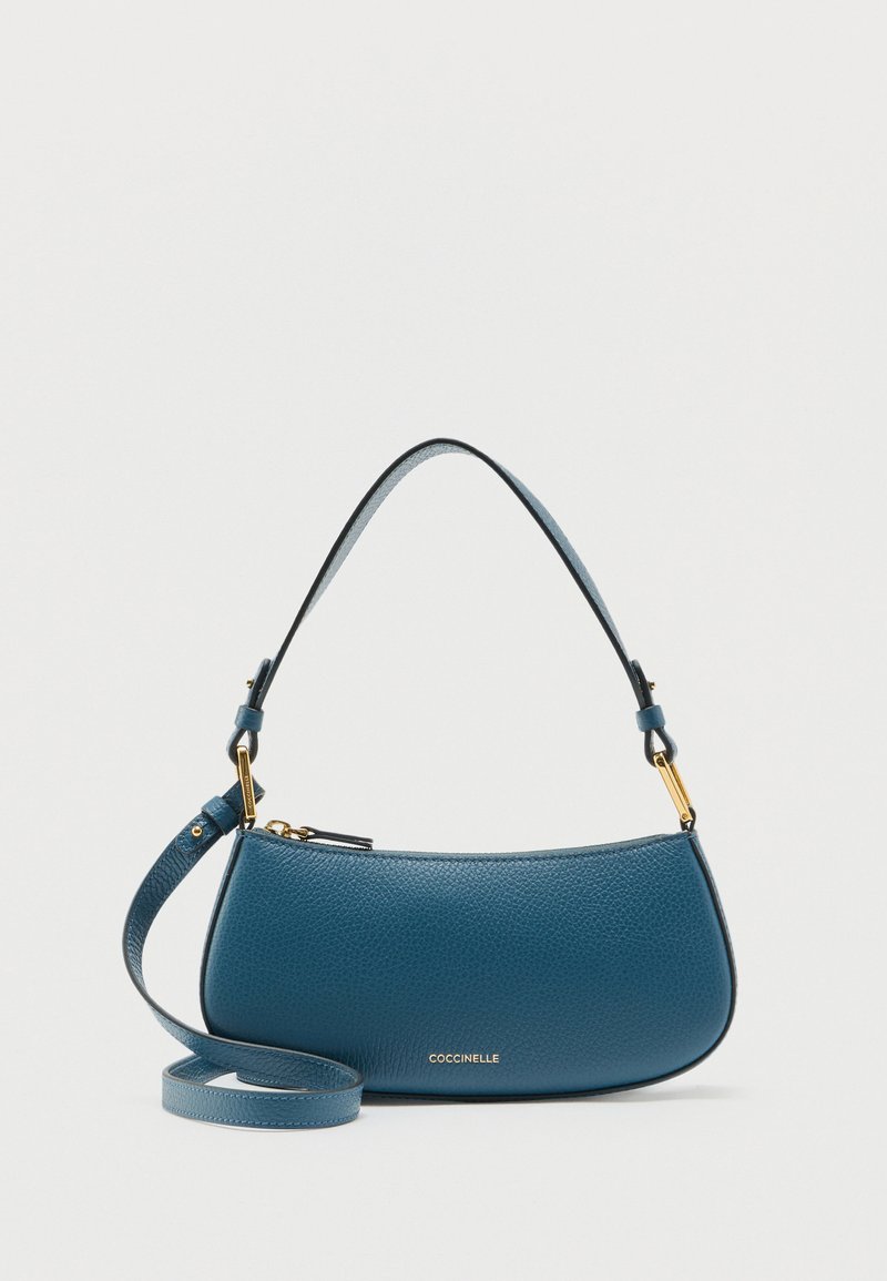 Μπλε υφασμάτινη δερμάτινη τσάντα με χρυσά κούμπωμα, κοντή λαβή, μακριά ρυθμιζόμενη ράβδο και λογότυπο Coccinelle στο εμπρόσθιο μέρος.