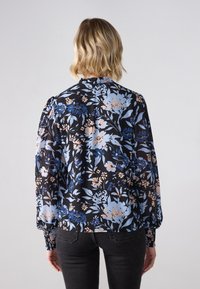 Floral blouse with long sleeves, black background, blue and peach flowers, textured fabric, smocked cuffs, and gathered shoulders.