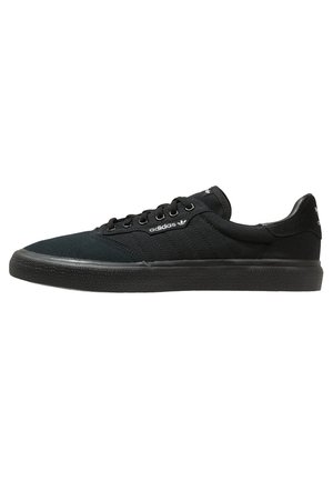Zapatilla Adidas negra de perfil bajo con cordones delanteros, suela de goma texturizada y logo blanco de Adidas en el lateral y en la lengüeta del talón.
