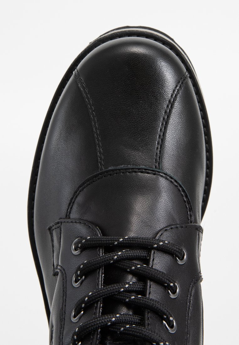 Schwarze Lederstiefel mit runder Zehenform, fünf Ösen Schnürverschluss mit schwarz-weißen Schnürsenkeln und kontrastierenden Nähdetails.