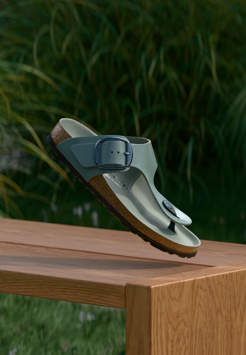 Γκρι και καφέ σανδάλια με λουράκι και μεταλλικό πόρπη, διαθέτουν διαμορφωμένο πέλμα και υφή στη σόλα, εκτεθειμένα πάνω σε ξύλινη επιφάνεια.