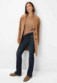 Kamelwollmischung Mantel mit großen Knöpfen, beigem Strickpullover, dunkelblauen Jeans und Ankle Boots im Leopardenmuster. Glattes, figurbetontes und tailliertes Design.