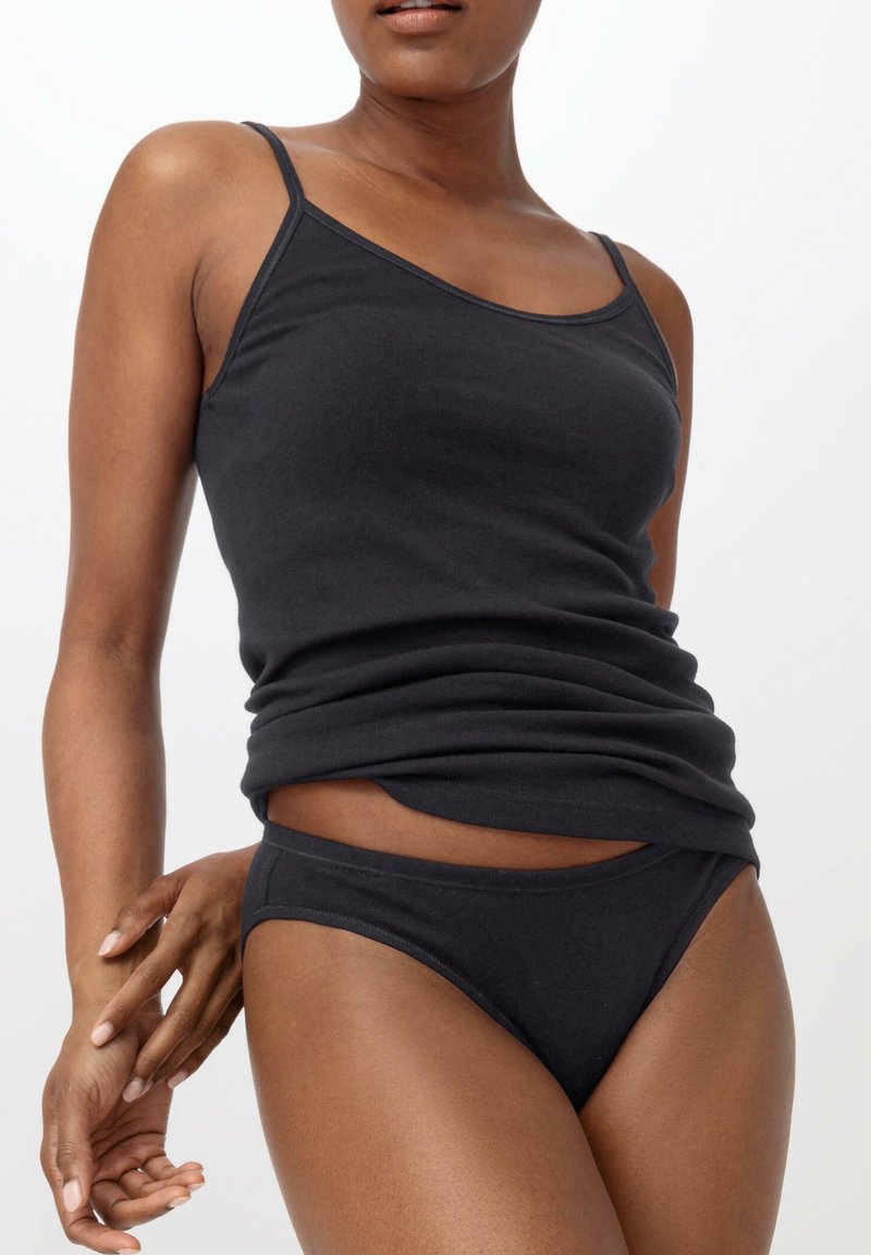Schwarzes Baumwoll-Camisole mit dünnen Trägern, kombiniert mit passenden schwarzen Slips. Glatte Textur, körperbetontes Design, minimalistischer Stil.