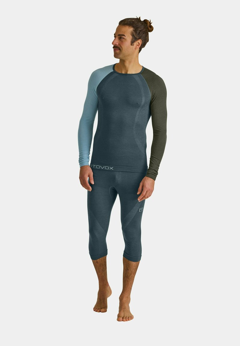 Lightweight performance base layer set in gradient blue and green hues. Composed of soft, stretchy material with long sleeves and form-fitting design.