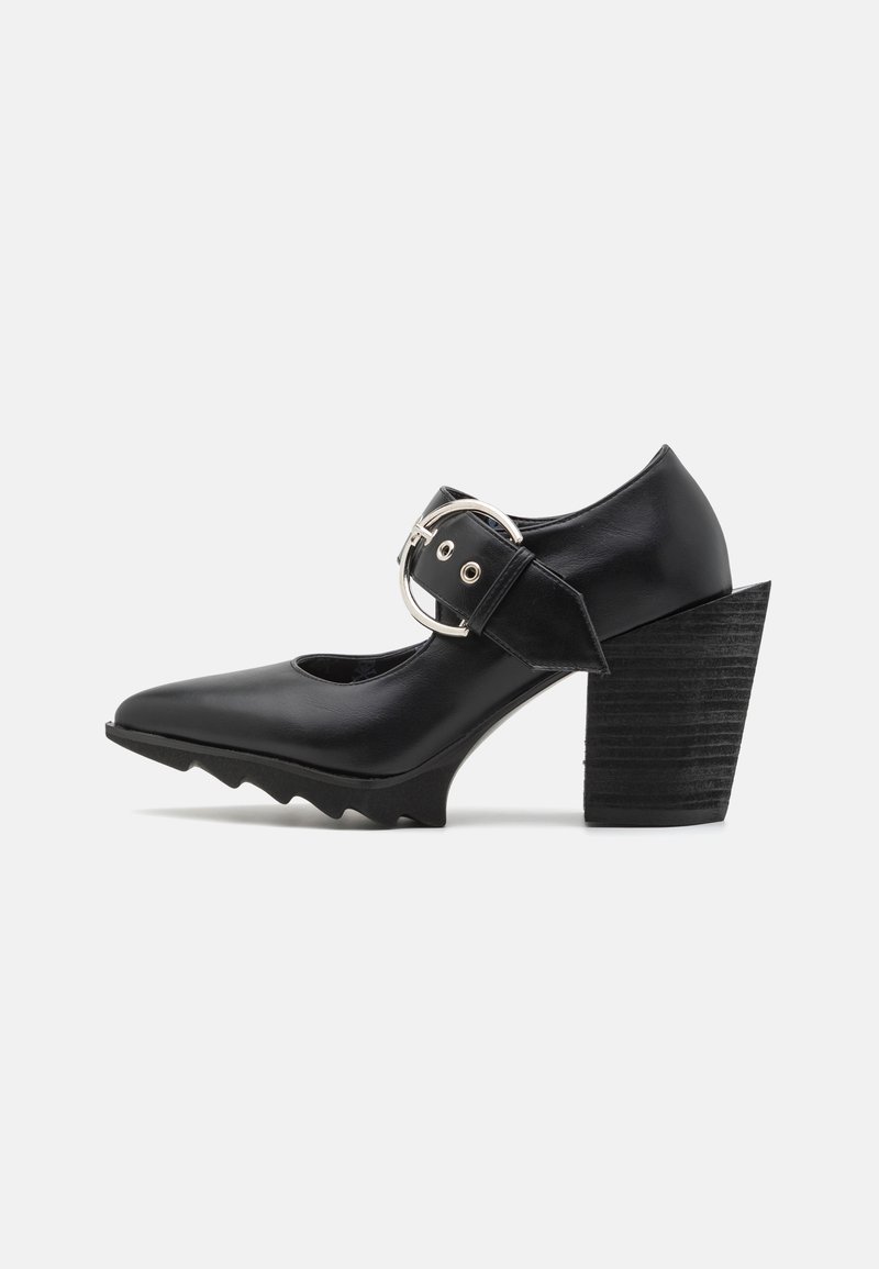 Zapato de tacón alto negro con punta afilada, tacón en bloque texturizado y correa ancha en el tobillo con hebilla plateada y herrajes circulares.
