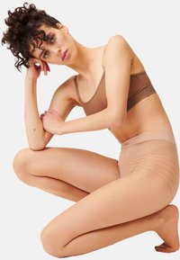 Set di reggiseno e slip in tonalità marrone chiaro, realizzato in materiale morbido e elasticizzato. Il reggiseno ha spalline sottili e un branding discreto; gli slip presentano una texture liscia.