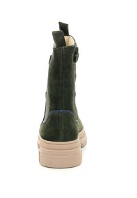 Botín de ante verde con suela de goma beige. Presenta una cinta en el talón y detalles de costura a lo largo de las costuras.