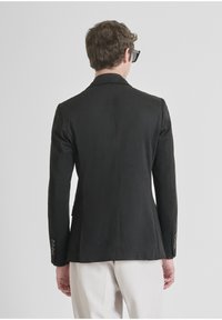 Blazer nero con una texture liscia, design a un petto, vestibilità slim e rever a punta. Presenta polsini con bottone e un taglio su misura.