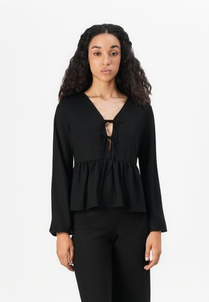 Schwarzes langärmliges Oberteil mit V-Ausschnitt und Bindedetail an der Vorderseite. Verfügt über eine Peplum-Taille und eine weiche Textur. Einfaches und minimales Design.