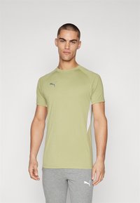 T-shirt de sport vert à manches courtes, avec un logo gris sur la poitrine et des panneaux latéraux blancs, fabriqué dans un matériau lisse et léger.